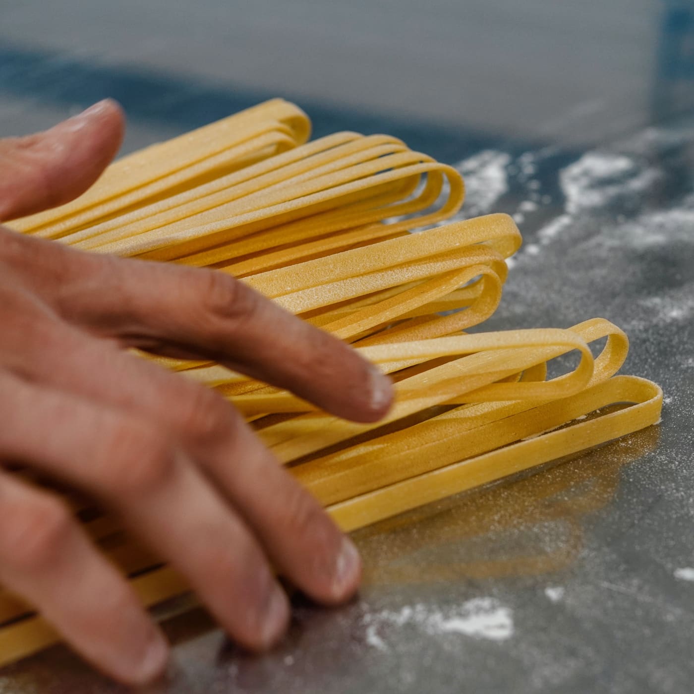 Fettuccine fraîchement tréfilées entre les mains du pastaio